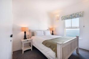 a white bedroom with a large bed with a window at Santorini Perissa Seaview Apartment in Shakaskraal