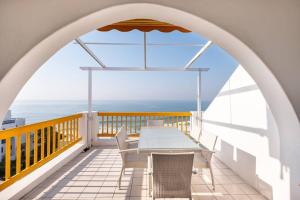 una mesa y sillas en un balcón con vistas al océano en Santorini Perissa Seaview Apartment en Shakaskraal