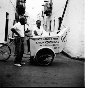 two men standing next to a cart with a sign at HOME SWEET HOME in Sammichele di Bari