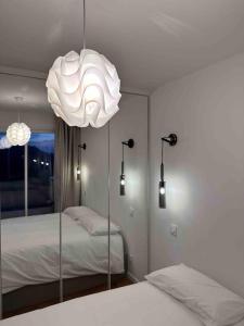 a room with two beds and a large white chandelier at Appartement rénové entre terre et mer avec piscine in Calenzana