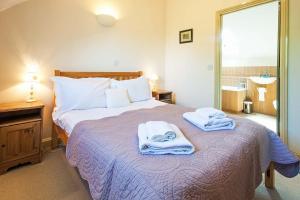 a bedroom with a bed with towels on it at Mill Village 59, Millstream Cottage - P in Somerford Keynes +16 photos