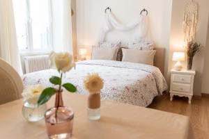 - une chambre avec un lit blanc et une table fleurie dans l'établissement La Fée Maison, à Châtel-sur-Moselle