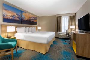 a hotel room with a bed and a flat screen tv at Days Inn & Suites by Wyndham Denver International Airport in Denver