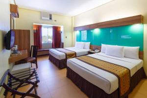 Habitación de hotel con 2 camas y escritorio en Microtel by Wyndham Davao en Davao