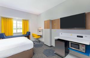 a hotel room with a bed and a flat screen tv at Microtel Inn and Suites by Wyndham in Opelika