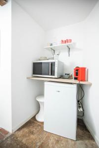 a white kitchen with a microwave and a refrigerator at Oustaou de Betty et Bob in Le Cailar