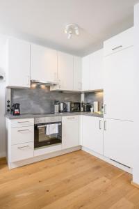 una cucina con armadietti bianchi ed elettrodomestici in acciaio inossidabile di Cozy Ottakring a Vienna