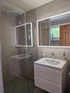 ein Bad mit einem Waschbecken, einer Dusche und einem Spiegel in der Unterkunft Chesa Mutaun in Silvaplana