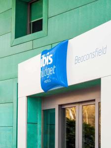 un panneau bleu et blanc sur le côté d'un bâtiment dans l'établissement ibis budget Beaconsfield, à Beaconsfield
