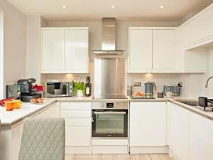 une cuisine avec des armoires blanches et un four à plaques de cuisson dans l'établissement Number 10, Montpellier Apartments, Teignmouth, à Teignmouth 25 autres photos