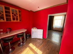 una cocina con paredes rojas, encimera y taburetes en Apartamenti, en Riga