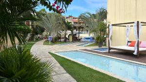 una piscina con una silla y una hamaca junto a un edificio en Flat temático Solar Água, en Pipa