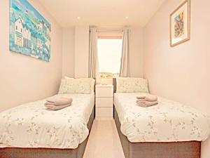 two beds in a small room with a window at Number 10, Montpellier Apartments, Teignmouth in Teignmouth