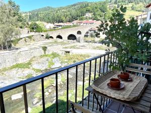 uma mesa numa varanda com vista para uma ponte em Apartamento colgante al río con vistas al puente em Camprodon