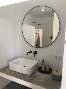 W łazience znajduje się biała umywalka i lustro. w obiekcie Casa Trece w mieście Iznájar