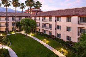 an exterior view of a building with a lawn and palm trees at DoubleTree by Hilton Ontario Airport in Ontario