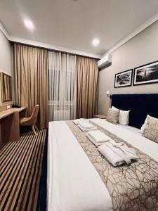 ein Hotelzimmer mit einem großen Bett und einem Schreibtisch in der Unterkunft Bristol Hotel Tashkent in Taschkent