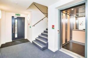 un escalier dans un bâtiment avec une porte noire dans l'établissement Number 10, Montpellier Apartments, Teignmouth, à Teignmouth