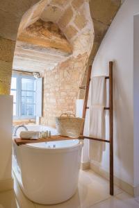 a bath tub in a bathroom with a stone wall at Predi Son Jaumell Hotel Rural in Capdepera