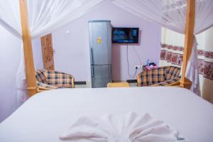 1 dormitorio con 1 cama con 2 sillas y nevera en Mzunguu Safari Lodge en Usa River