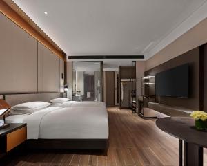 a bedroom with a large bed and a flat screen tv at Hyatt Regency Shanghai Songjiang in Songjiang