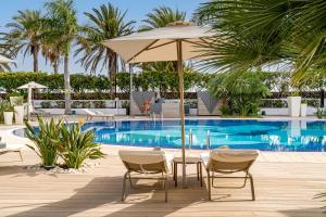 a patio with an umbrella and chairs and a pool at Sir Anthony in Playa de las Americas