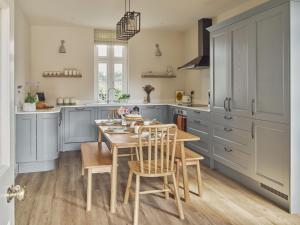 una cocina con armarios azules y una mesa y sillas de madera. en Bridge House at Woodhall Estate en Hertford