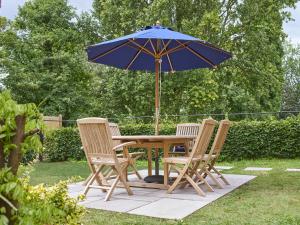 a wooden table with four chairs and an umbrella at Bridge House at Woodhall Estate in Hertford
