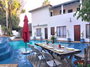 un patio con mesa y sillas junto a una piscina en The Goldstone, en Pretoria