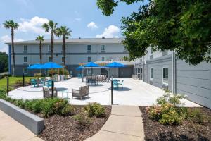 un patio con mesas, sillas y sombrillas azules en TRYP by Wyndham Tallahassee North I-10 Capital Circle en Tallahassee