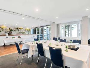 a dining room with white tables and blue chairs at Peppers Manly Beach in Sydney
