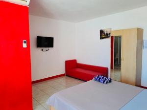 um quarto com uma cama vermelha e uma cadeira vermelha em Spacious Private Rooms with Communal Kitchen em Grand Gaube