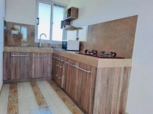 a large kitchen with wooden cabinets and a sink at Spacious Private Rooms with Communal Kitchen in Grand Gaube
