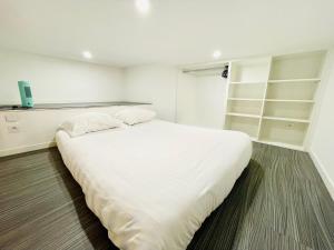 un grande letto bianco in una stanza con scaffali di Lodge Nicolas, Hyper Centre a Nantes