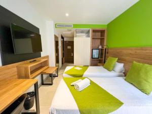 2 camas en una habitación con una pared verde en Hotel MG Poniente en Las Palmas de Gran Canaria