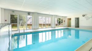 a large swimming pool with blue water in a building at Les Ecureuils B11 - Studio montagne 2 pers in Saint-Sorlin-dʼArves