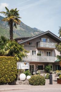 a building with a palm tree in front of it at Hotel Dorner B&B in Lagundo