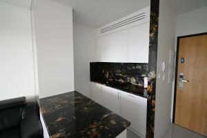 eine Küche mit weißen Schränken und einer schwarzen Arbeitsplatte in der Unterkunft Apartament Onyx Modern Tower in Gdynia