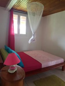 a bedroom with a bed with a pink lamp on a table at F1 studio Martinique in Quartier la Fleury Guiné