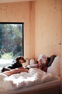 Eine Frau, die neben einem Hund auf einem Bett liegt. in der Unterkunft Slow Cabins Kinvara in Kinvara