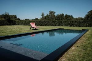 una silla rosa junto a la piscina en De verloren hoek, en Aarschot