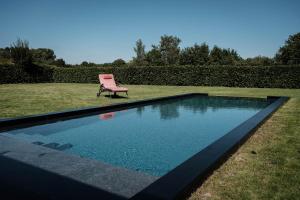 une chaise rose assise à côté de la piscine dans l'établissement De verloren hoek, à Aarschot