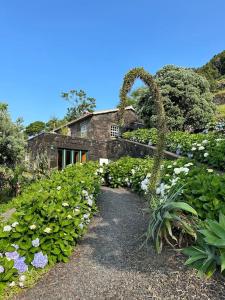 a garden with flowers and a stone house at Casa Pequena da Terra Alta in Santo Amaro