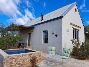 a house with a swimming pool and two chairs at Wolverfontein Karoo Cottages in Ladismith