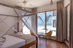 a bedroom with a bed and a view of the beach at S&S HOTEL in Jambiani