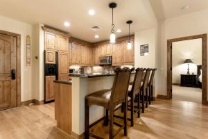 a kitchen with wooden cabinets and a bar with chairs at B107 Beaver Creek Landing condo in Beaver Creek
