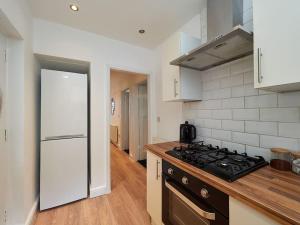 uma cozinha com um fogão e uma parede branca em House In Birmingham - Perfect For Contractors - Working Professionals - Driveway - 14 Mins To NEC - 13 Mins to BHX em Birmingham