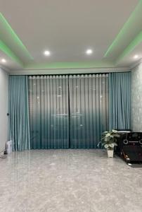 um quarto com uma grande porta de vidro com cortinas verdes em บ้านนายหัว ก ชุมพร em Ban Tha Samet (1)