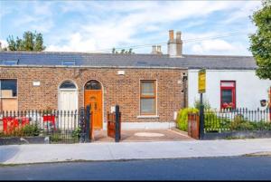 uma casa de tijolos com uma porta laranja numa rua em Spacious 2-bedroom property, minutes from city. em Dublin