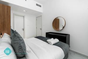 Schlafzimmer mit einem großen weißen Bett und einem Spiegel in der Unterkunft Deluxe 1 Bedroom In Oasis in Abu Dhabi